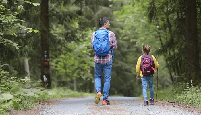 Man and girl walking on forest path